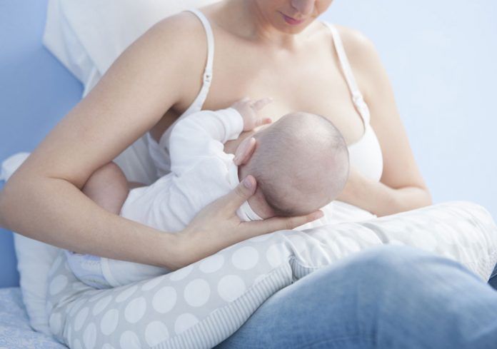 Breastfeeding mom using a feeding pillow