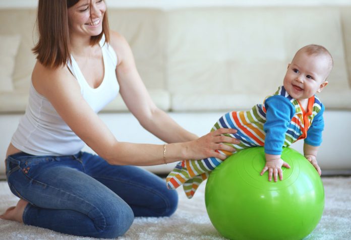 A mother and baby playing with a gymnastic ball