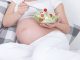A pregnant woman eating a salad with tomatoes