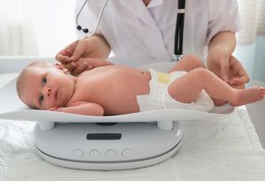 A doctor weighing a newborn baby