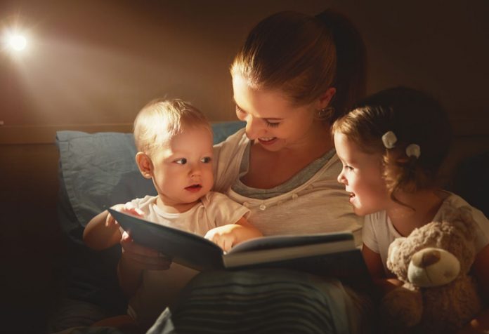 Mother reading bedtime stories to her son and daughter