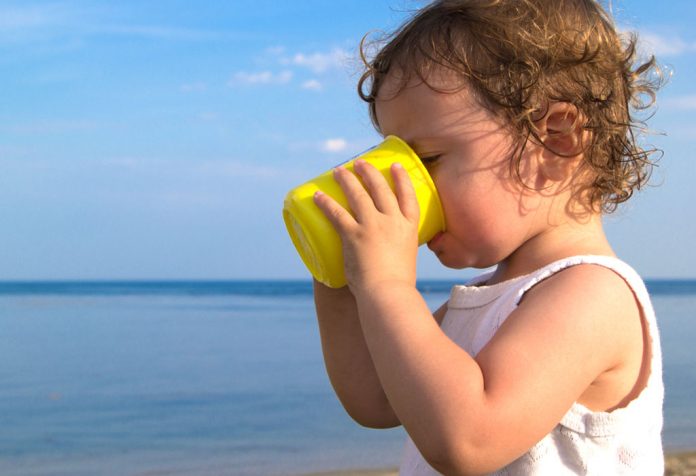 A child drinking water from a yellow mug