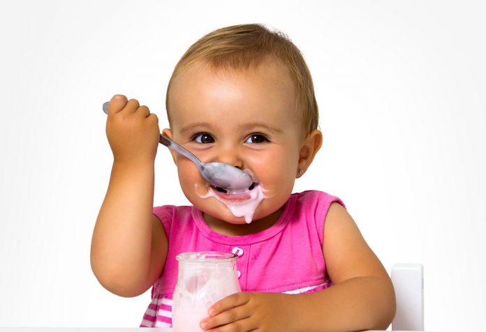 A baby girl eating yogurt
