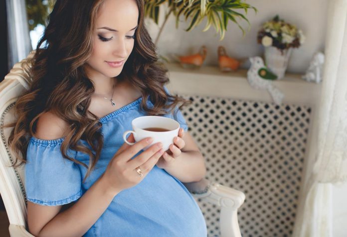 A pregnant woman holding a cup of coffee