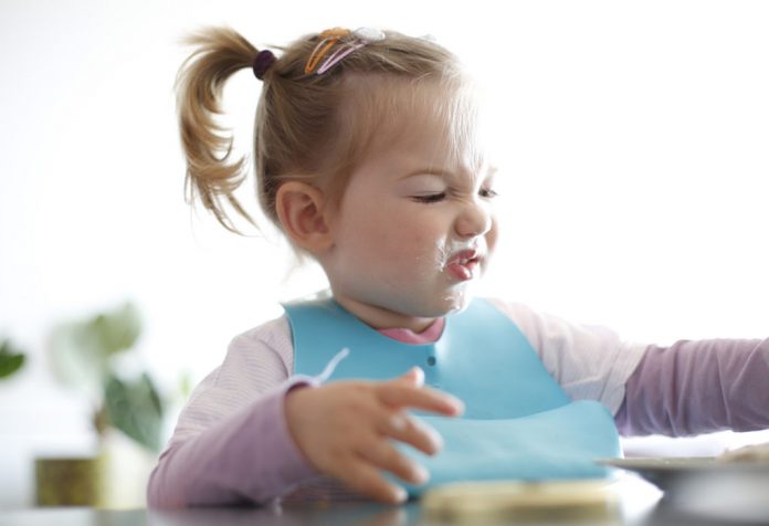 A little girl making faces while eating