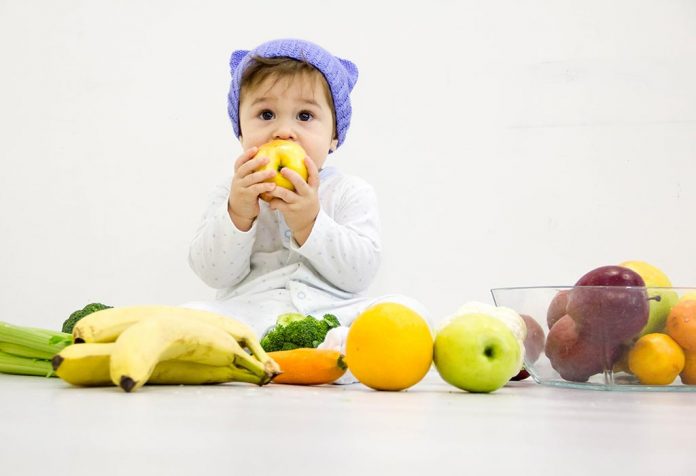 A baby surrounded by fruits and vegetables