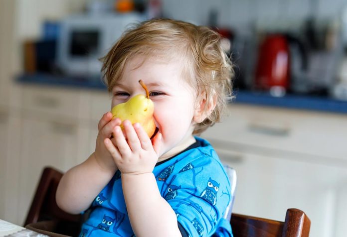 A baby trying to eat pear