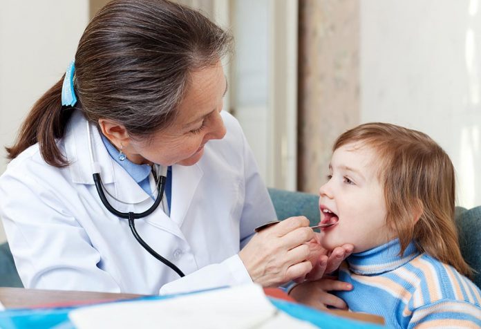 A doctor checking a little girl's throat