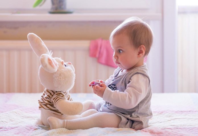 A 10 month-old baby playing with a bunny