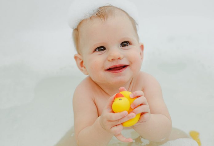 A baby playing with toy ducks in a bath tub