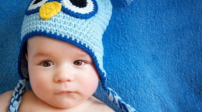 A 16 week-old baby wearing an owl hat